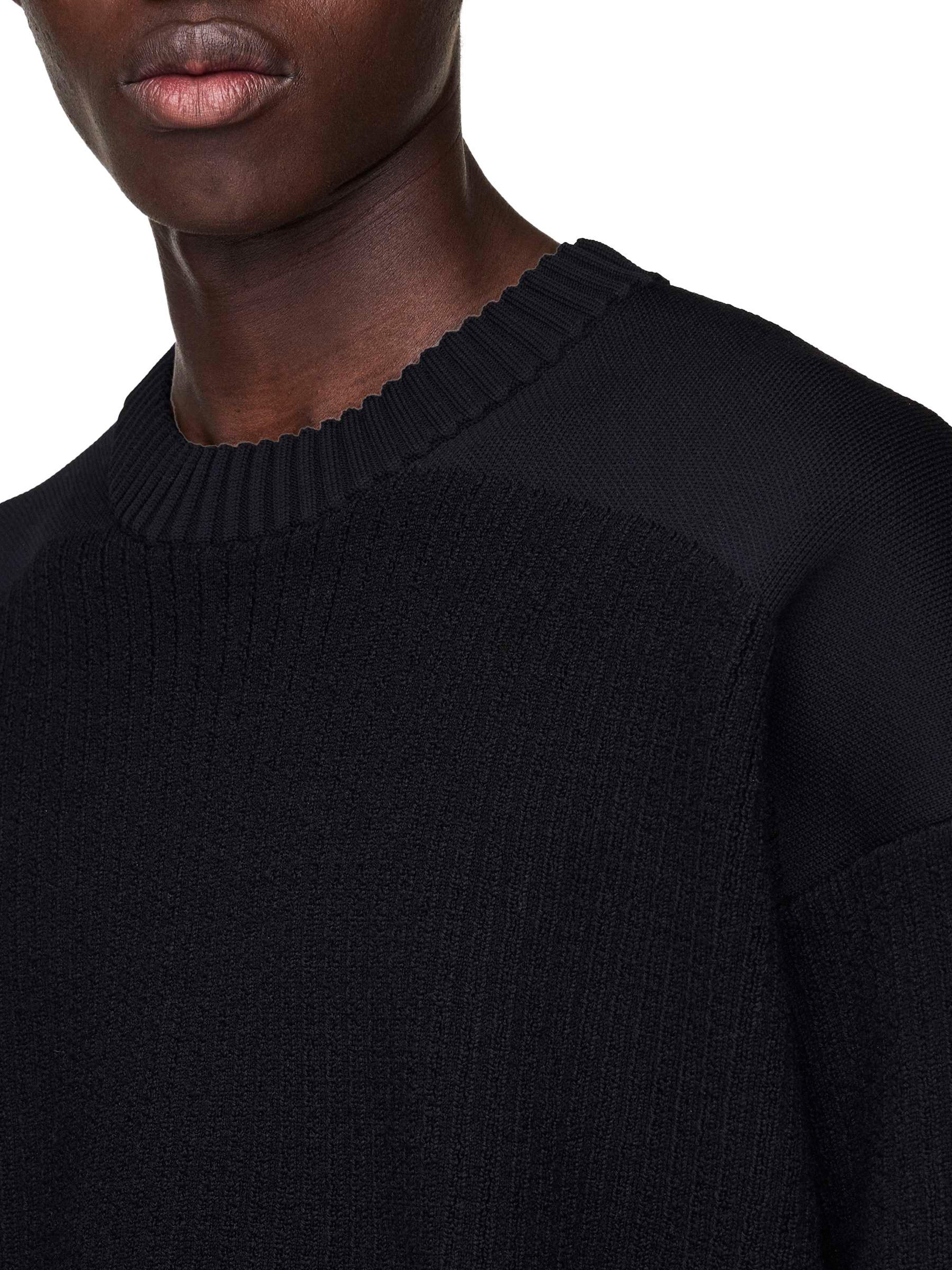 Close-up of a person wearing a black sweater with a white background