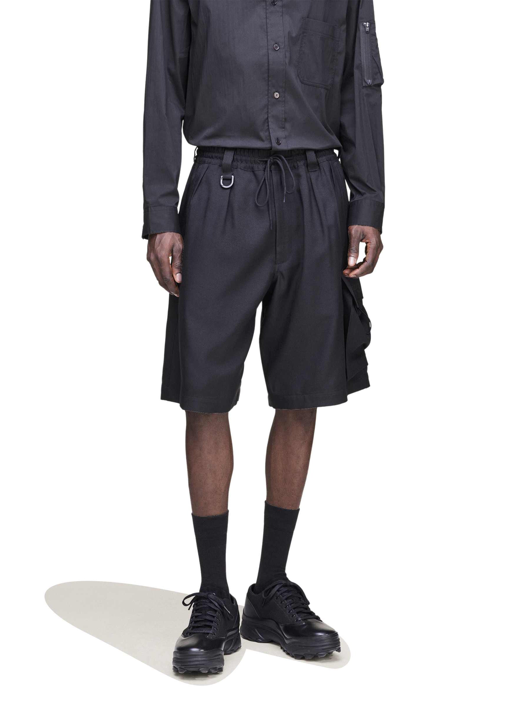 Close-up front view of a male model wearing the Y-3 Sport Uniform Cargo Shorts in Black, showing the twill texture and heat-transfer Y-3 logo.