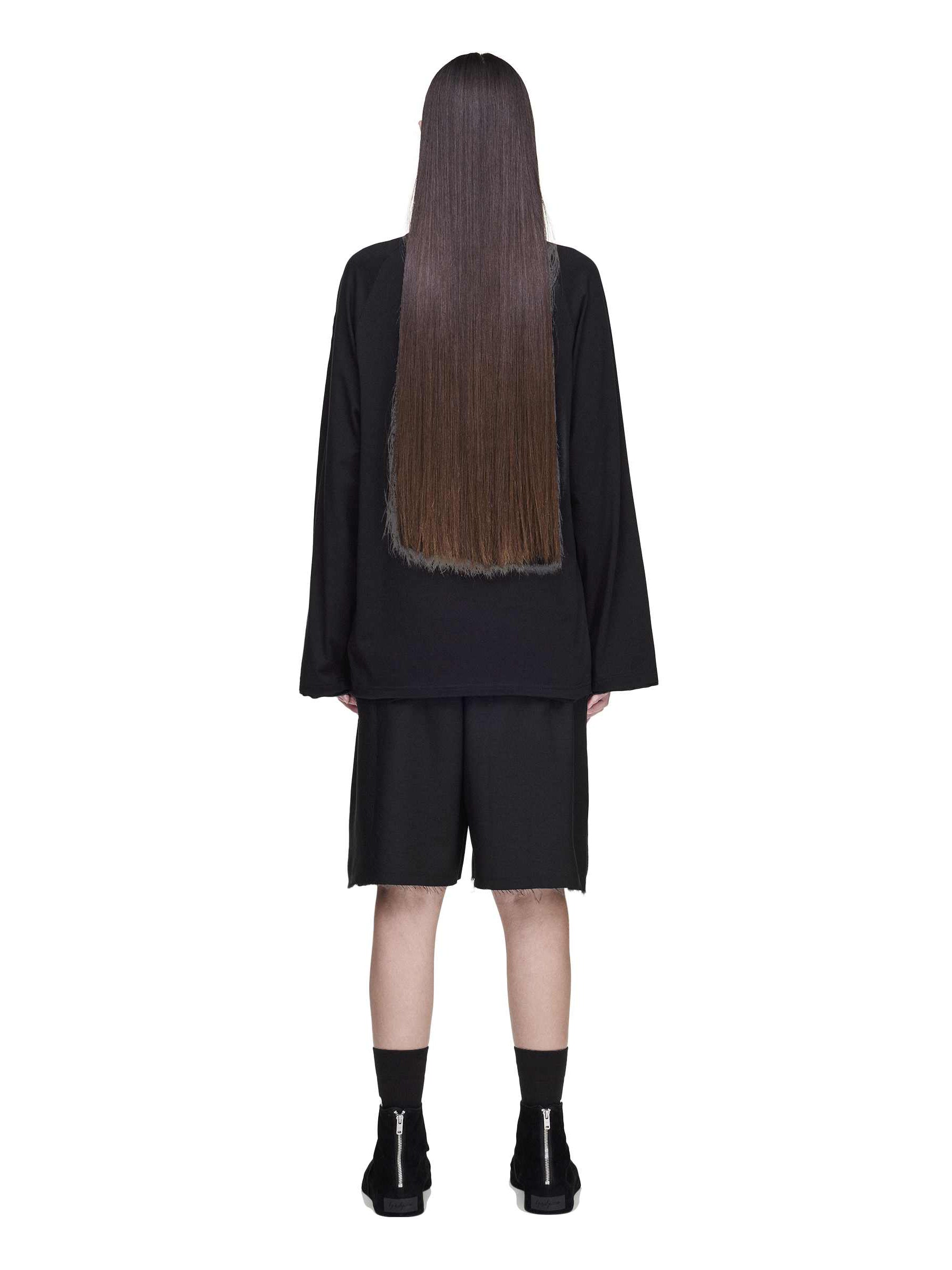 Back view of a female model wearing the Y-3 Summer Run 3-Stripes Shorts in black, emphasizing the relaxed fit and subtle frayed detailing.