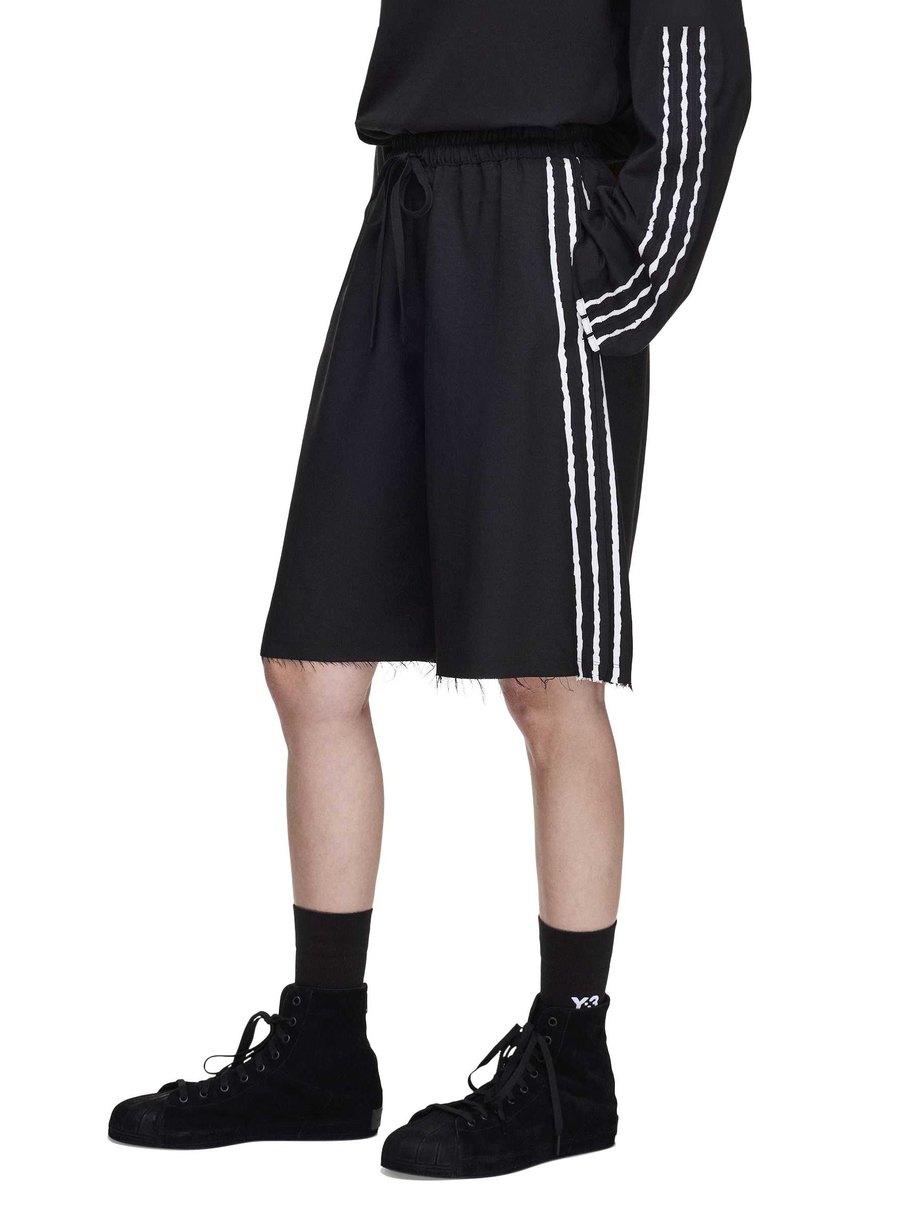 Detail close-up of the Y-3 Summer Run 3-Stripes Shorts worn by a female model, showing frayed detailing and contrast stripe finish.