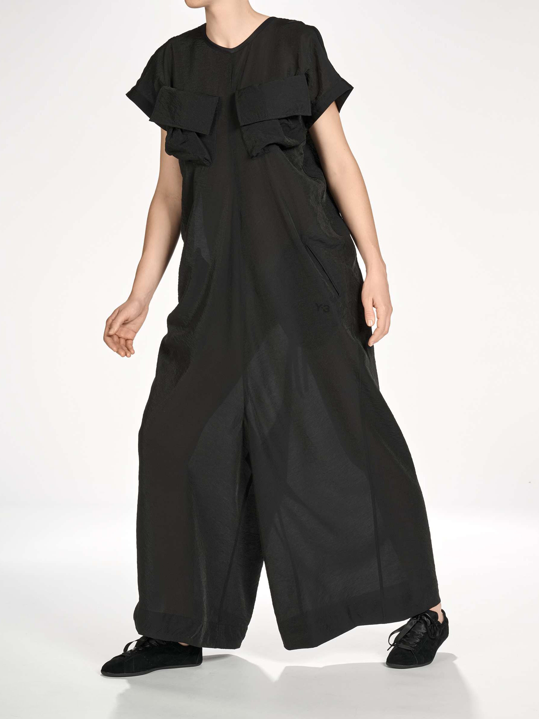 Side view of a female model wearing the Y-3 Women’s Utility Dress in Black, emphasizing the fluid movement and relaxed fit.