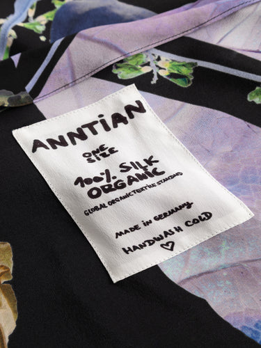 Close-up of the Anntian Asymmetric Top showing the dark floral print and the Anntian brand label at the neckline.