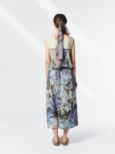 Back view of model wearing the Anntian Silkdress in Print Q, a sleeveless relaxed-fit silk dress in a multicolour floral print with blue tones, featuring an elastic waist with drawstring