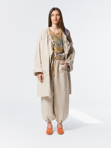 Front view of model wearing the Anntian Trench Jacket Hemp in Natural, an off-white loose-fit hemp jacket with an adjustable drawstring neckline, one size