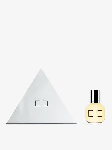 Triangle-shaped white box and a yellow perfume bottle with a silver cap on a white background