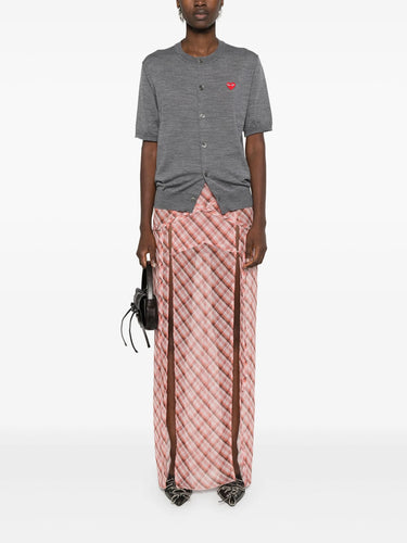 Female model wearing the short-sleeve cardigan with a red heart logo from Comme des Garcons Play on a white background