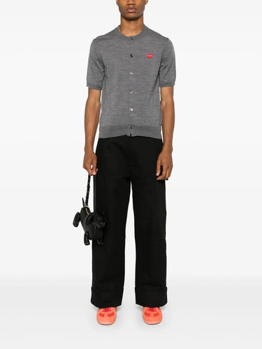 Male model wearing the short-sleeve cardigan with a red heart logo from Comme des Garcons Play on a white background