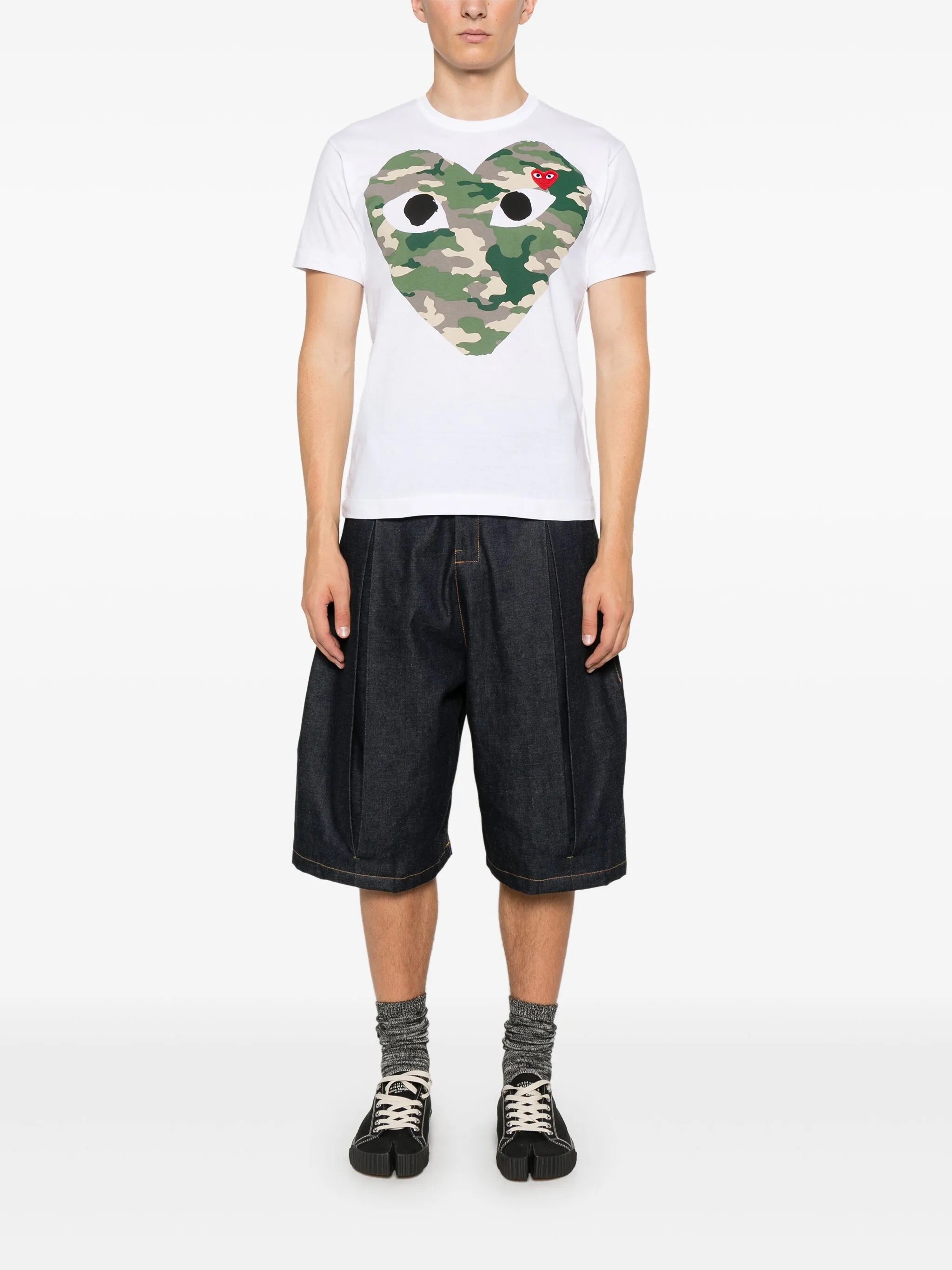 Model wearing Comme des Garçons Play Unisex Short Sleeve Camouflage Shirt in white with camouflage heart graphic and relaxed fit