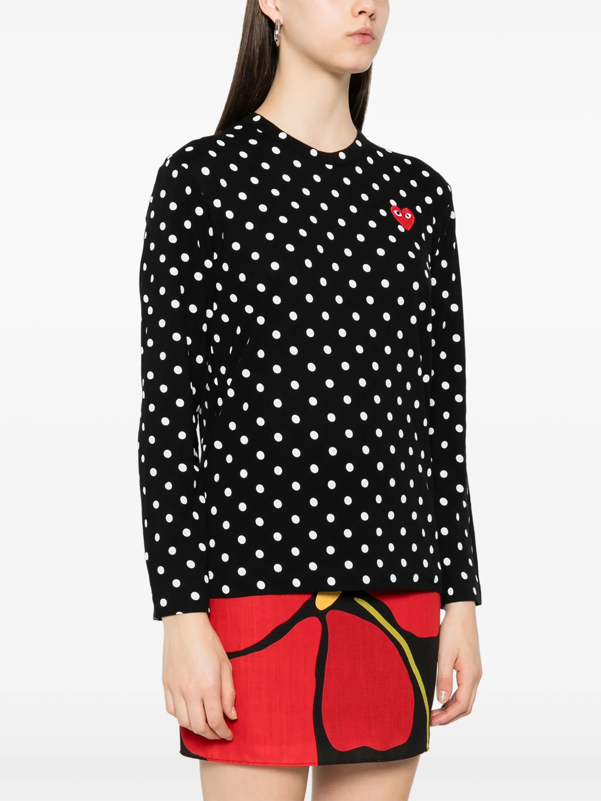 Model wearing Comme des Garçons Play black polka dot long sleeve shirt with round neckline and red heart chest logo