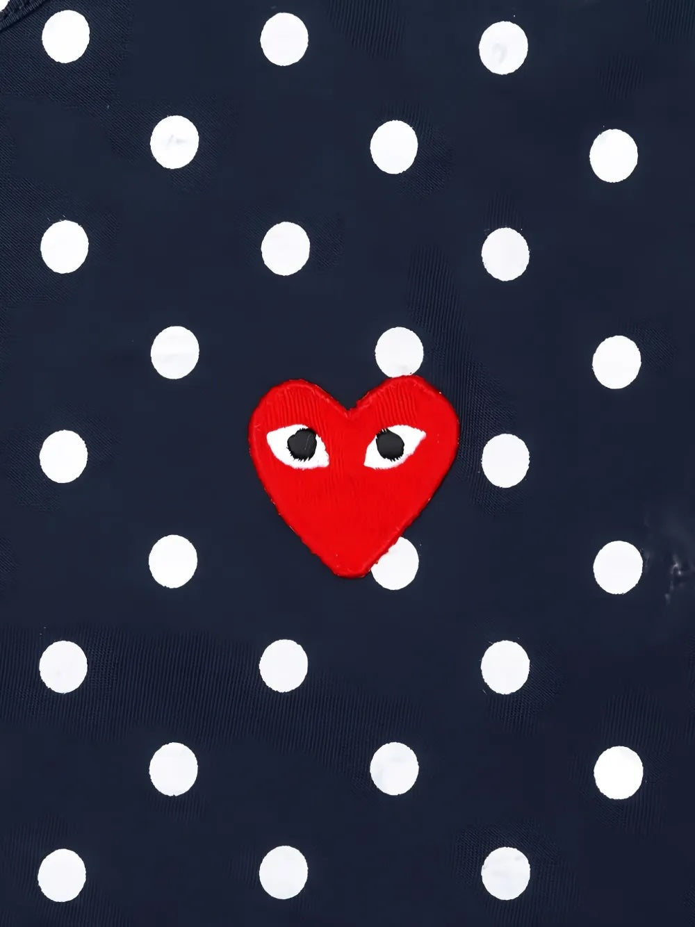 Close-up of Comme des Garçons Play navy polka dot shirt showing red embroidered heart logo and white dot print