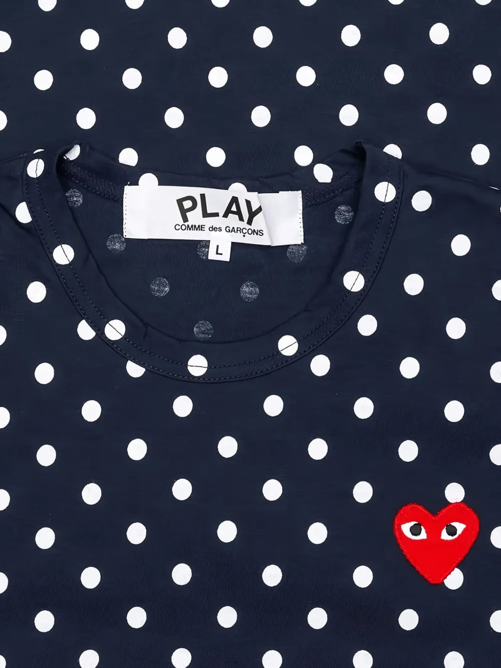 Close-up of Comme des Garçons Play Unisex Polka Dot Long Sleeve Shirt in navy showing round neckline, white polka dots and red heart chest logo