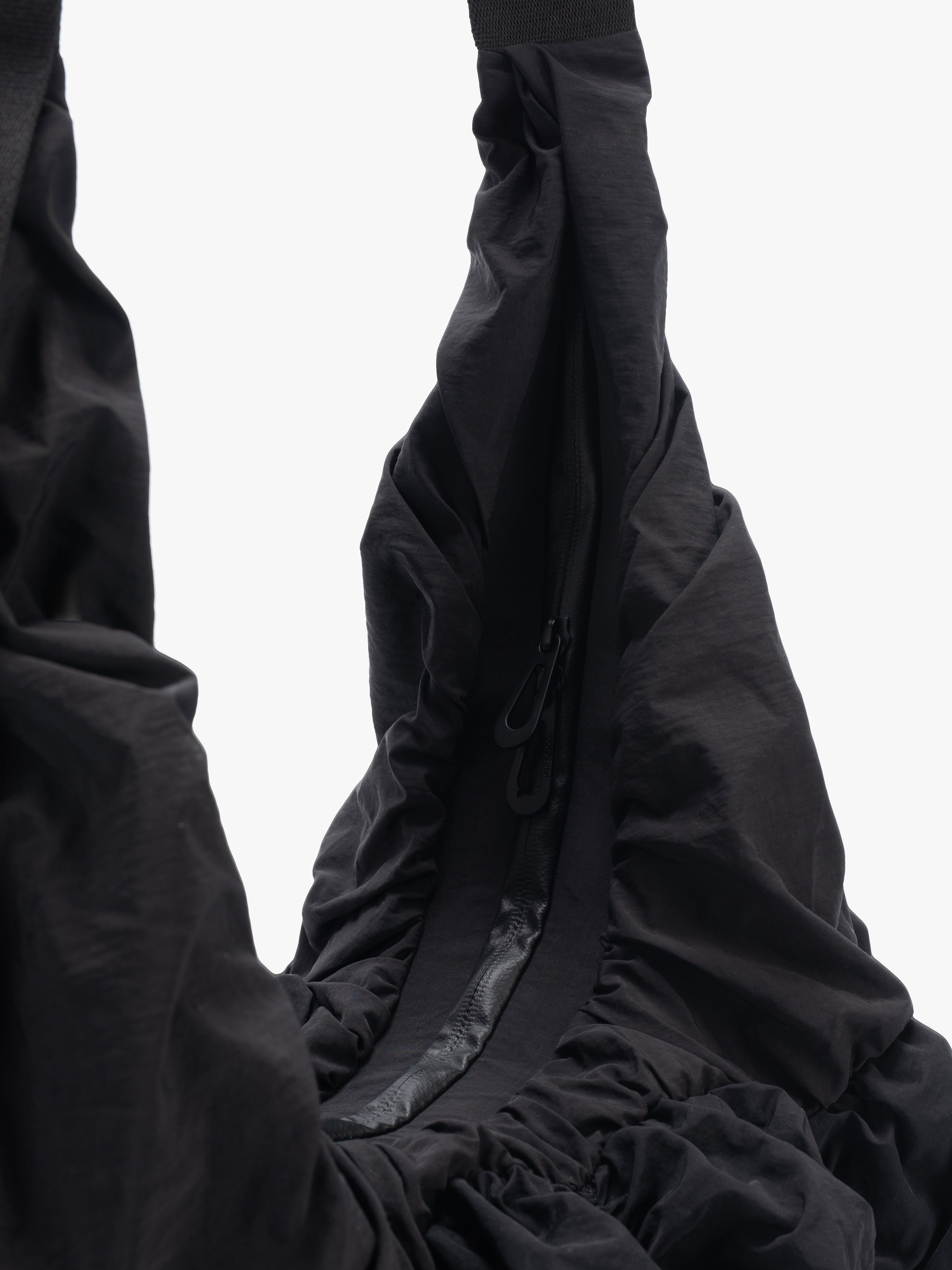 Closeup of Côte&Ciel Hyco S Otra Gathered crossbody bag in black, highlighting main compartment water-resistant zipper and internal security pockets.