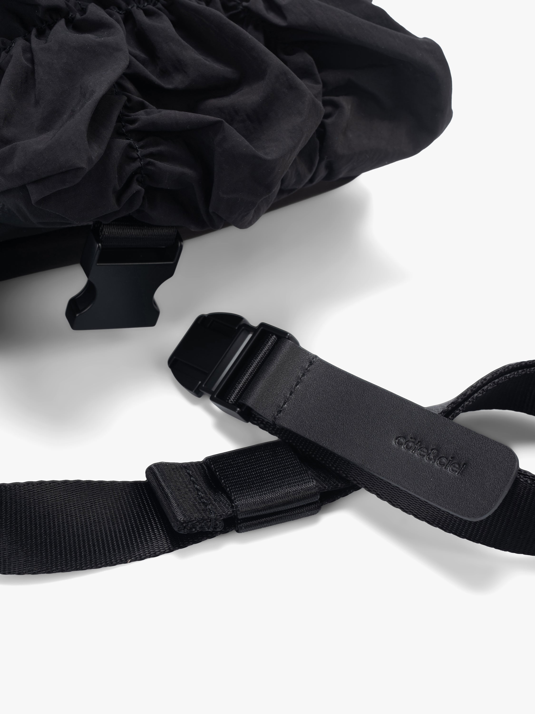 Closeup of Côte&Ciel Neva Gathered black bag, focusing on strap closure and functional design for crossbody or waist wear.