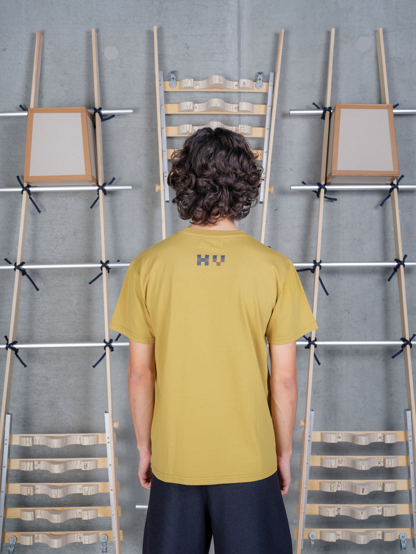 Model wearing Henrik Vibskov Cross Stitch Tee in Amer Green, back view.