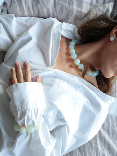 Woman lying down, wearing the opal moon bracelet from De Silang