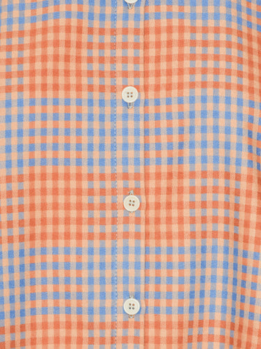 Close-up of a red-orange and blue checkered fabric with buttons.