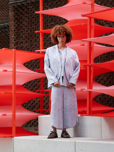 Front view of a model wearing the blazer, showing the floral texture, single-button closure, and structured yet relaxed fit.