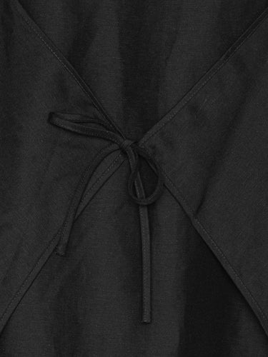 Closeup of Henrik Vibskov Beetle Dress in black, highlighting adjustable tie detail at front or back and textured fabric of SS26 design.