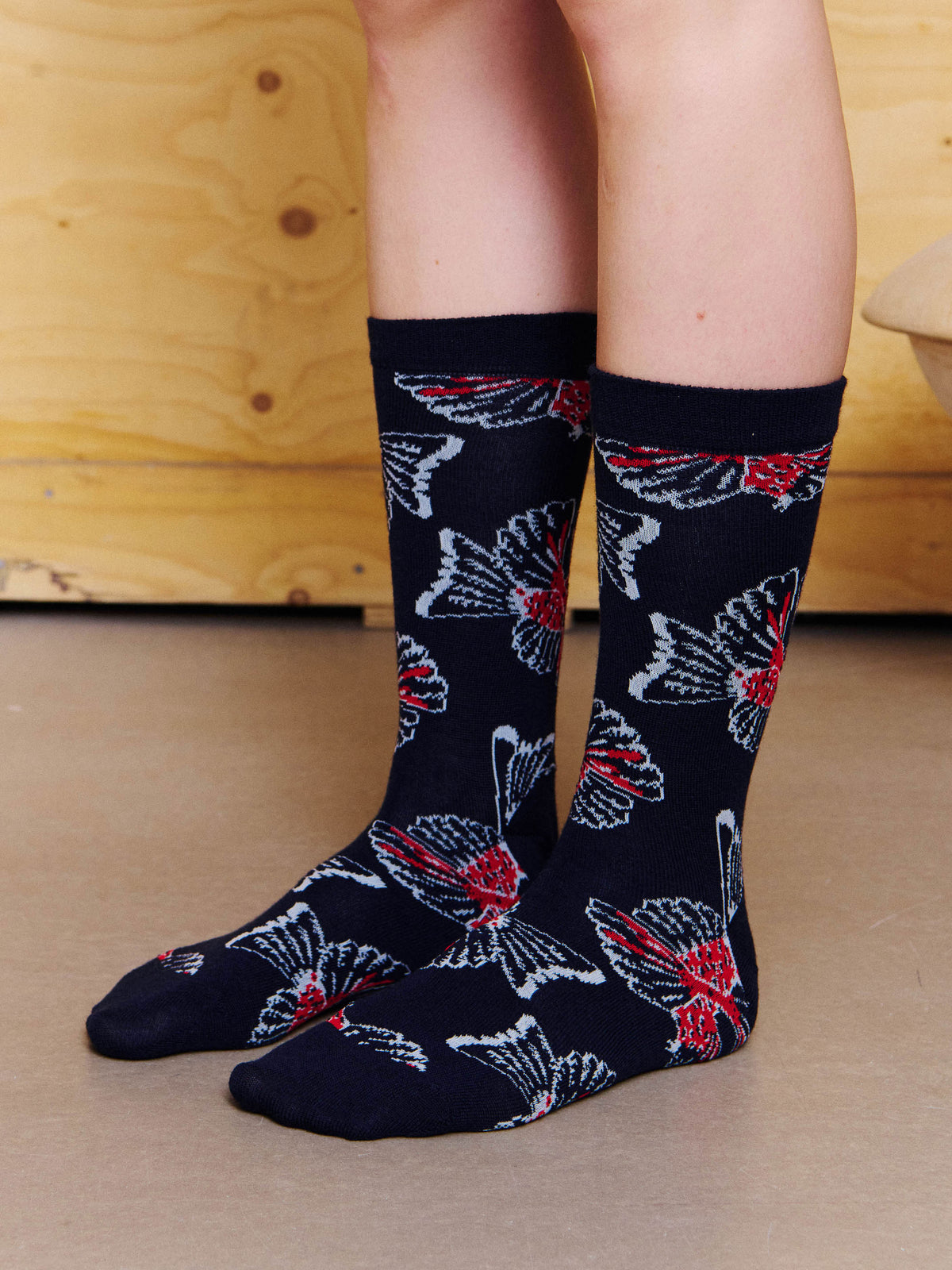 Henrik Vibskov Birdy Socks Anniversary in Navy Red Birdy worn side view, showing the mid-calf fit, ribbed cuff and repeated bird motif.