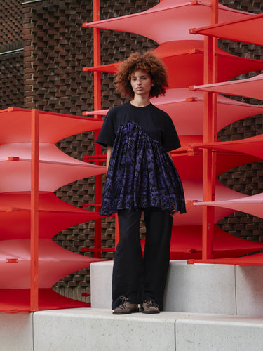Model wearing Henrik Vibskov Bon Chalant Tee in black, front view, loose fit with gentle volume and subtle black and purple floral print.