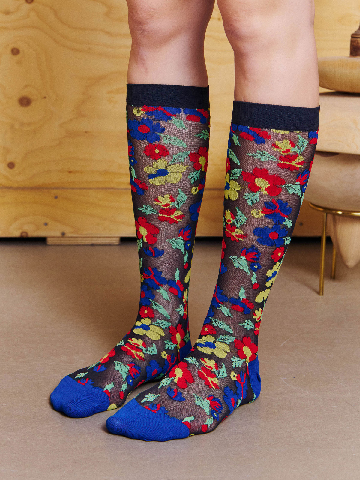Front view of model wearing the Henrik Vibskov Bouquet Socks in Blue Floral Affairs, showing the semi-sheer floral pattern and mid-calf fit.