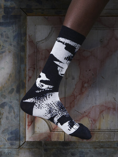 Close-up of a leg wearing the Bubble Wrap Socks in Black Bubble from Henrik Vibskov Spring/Summer 2026 Studio Collection, highlighting the black and white bubble-inspired pattern.