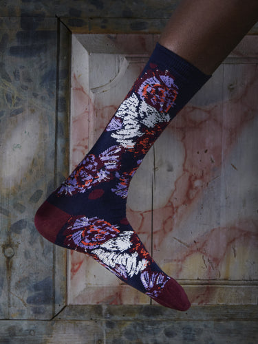 Close-up of a leg wearing the Chicken Socks in Navy Chickens from Henrik Vibskov Spring/Summer 2026 Studio Collection, highlighting the navy colour and multicoloured chicken-inspired details.