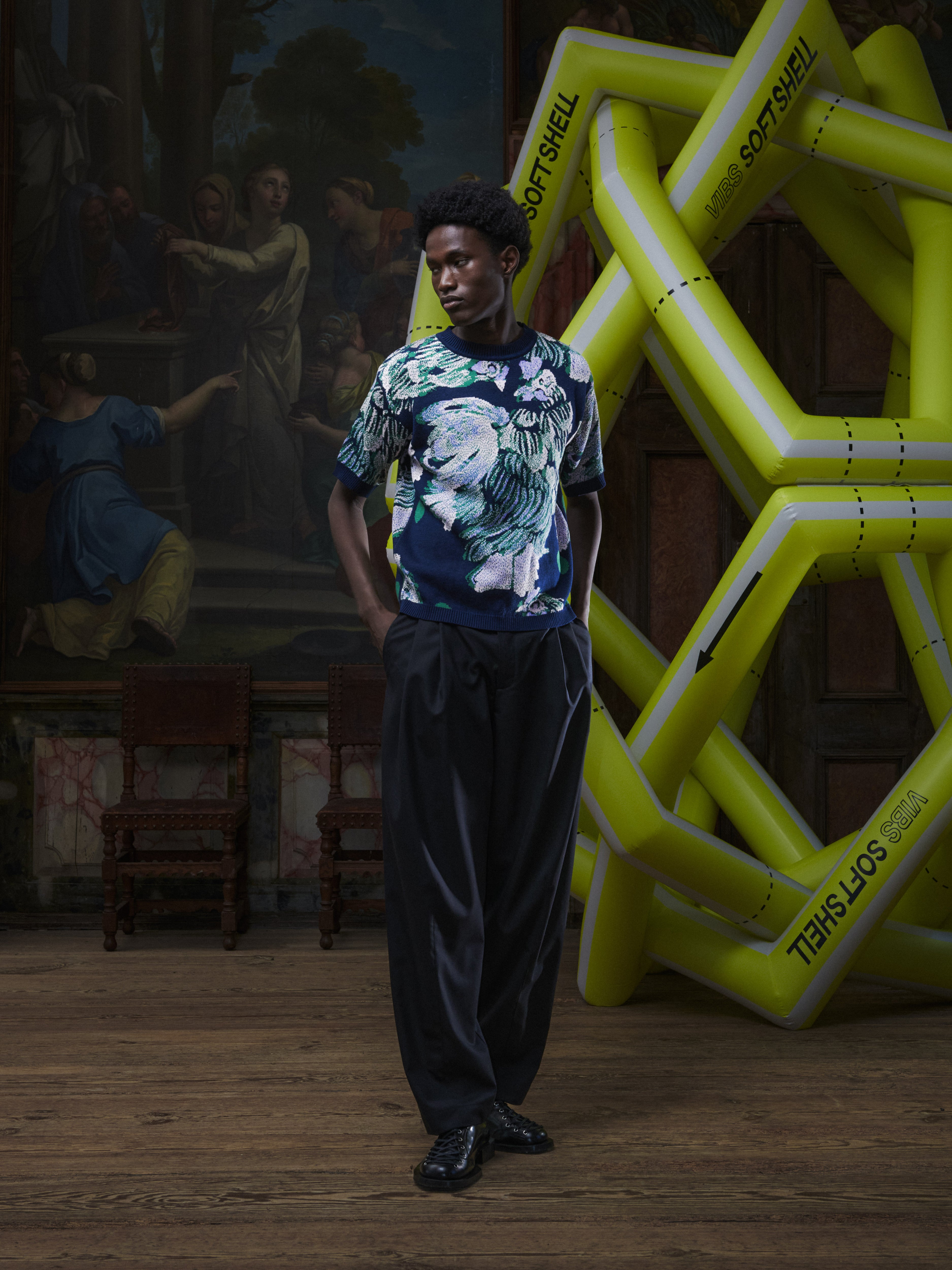 Front full-body view of a male model wearing the Chicken T Knit in Chicken Navy from Henrik Vibskov Spring/Summer 2026 Studio Collection, displaying the unisex fit, crew neck, and chicken motif.