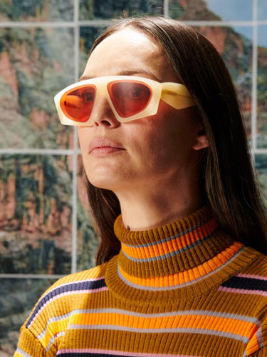 Person wearing a striped sweater and orange sunglasses with a colorful abstract background