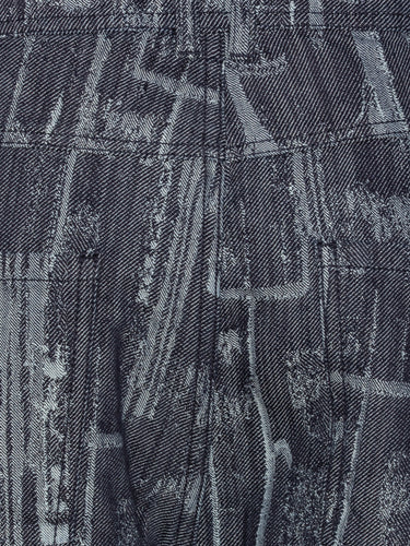 Close-up of the Curved Denim Pants showing the grey-blue denim texture, abstract instrument motif, and waistband detailing with belt loops.
