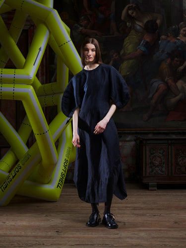 Model wearing the Double Bass Dress in Black, front view. Model is 185 cm and wears size S, showing the round neck, wide sleeves, and sculpted hourglass silhouette.