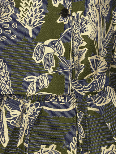 Close-up of the Garden of Eeden floral pattern highlighting the green, blue and white layered fabric and button detailing.