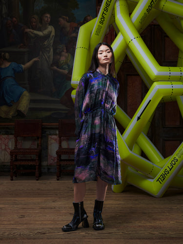 Model wearing the Henrik Vibskov Flat Dress in Foxes, front view. The model is 167 cm and wears size S, showing the round collar, adjustable waist drawstring, and flowing multicolour print.