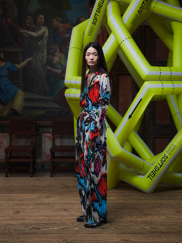 Model wearing the Henrik Vibskov Fold Plissé Pants in Carrots, front view. The model is 167 cm and wears size S, showing the colourful vegetable print, pleated texture, and relaxed straight-leg fit.