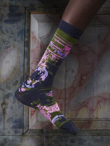 Close-up of a leg wearing the Foxy Socks in Black Foxy from Henrik Vibskov Spring/Summer 2026 Studio Collection, highlighting the black base and multicoloured fox-pattern design.