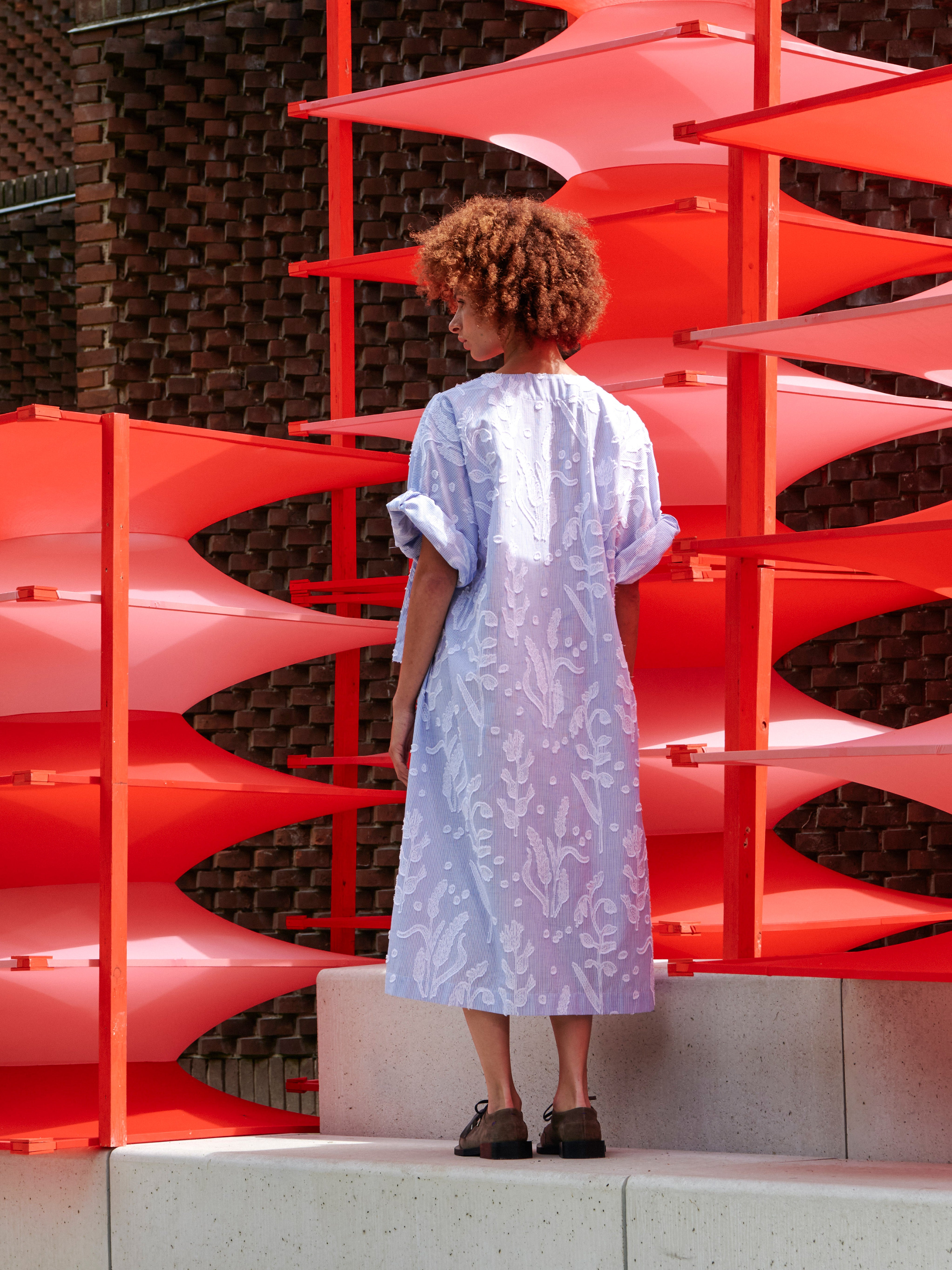 Back view of a model wearing the Insurance Dress, showing the relaxed fit and textured floral fabric.