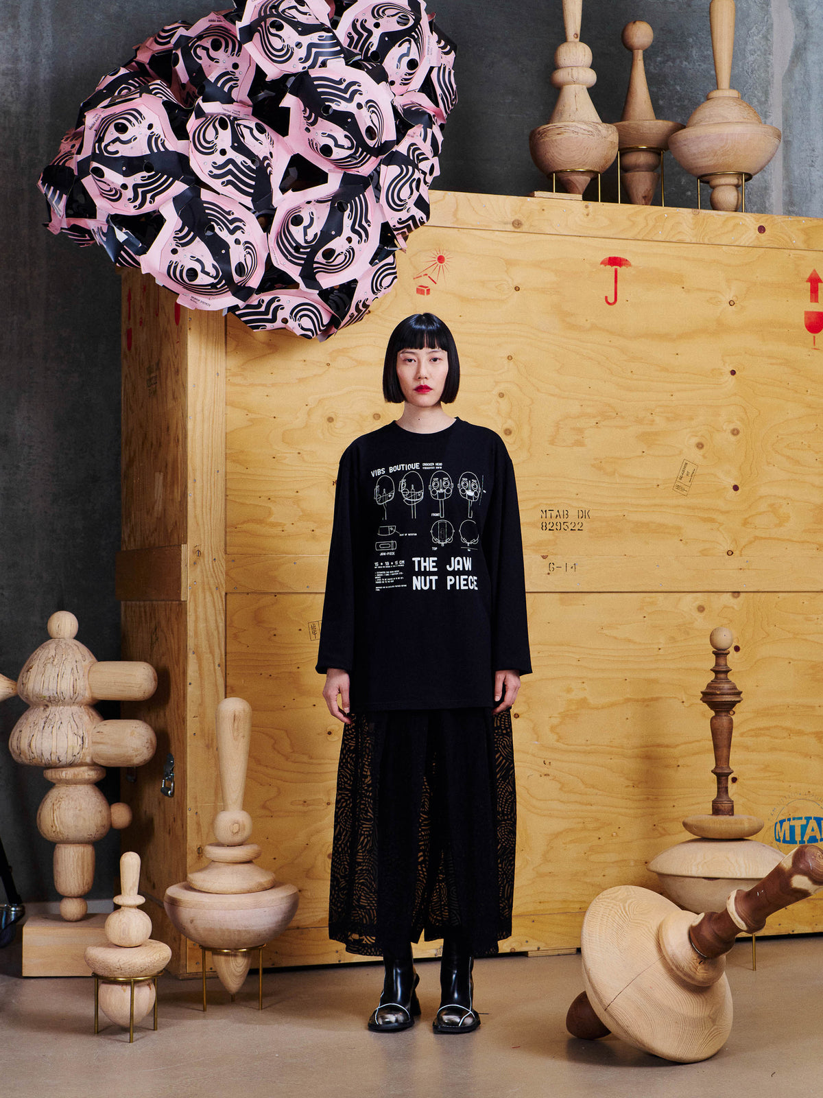 Model wearing Henrik Vibskov Jaw Nut Piece Tee in Black with oversized long-sleeve fit, white front graphic and black layered styling
