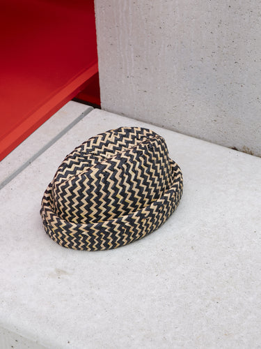 Newspaper Straw Hat in Black Natural Straw by Henrik Vibskov, opposite angled front view highlighting sculptural silhouette, chevron weave texture and voluminous crown with rolled brim, Spring/Summer 2026 Key Collection