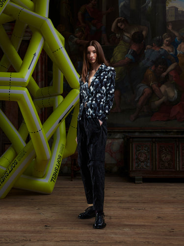 Model wearing the Henrik Vibskov Plissé Blazer in Bursting Eggs, front view. The model is 185 cm and wears size S, showing the fitted silhouette, classic blazer collar, and full plissé texture with abstract egg illustration.