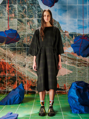 Woman in a black dress standing in front of a colorful abstract wall with blue rocks.
