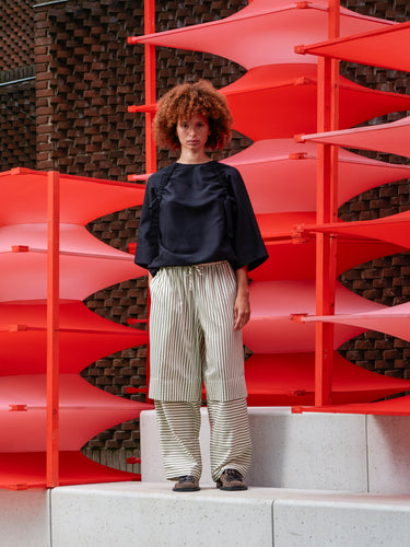 Front view of a model wearing the Shants Pants, showing the striped pattern, elastic waistband with drawstring, and relaxed wide-leg fit.