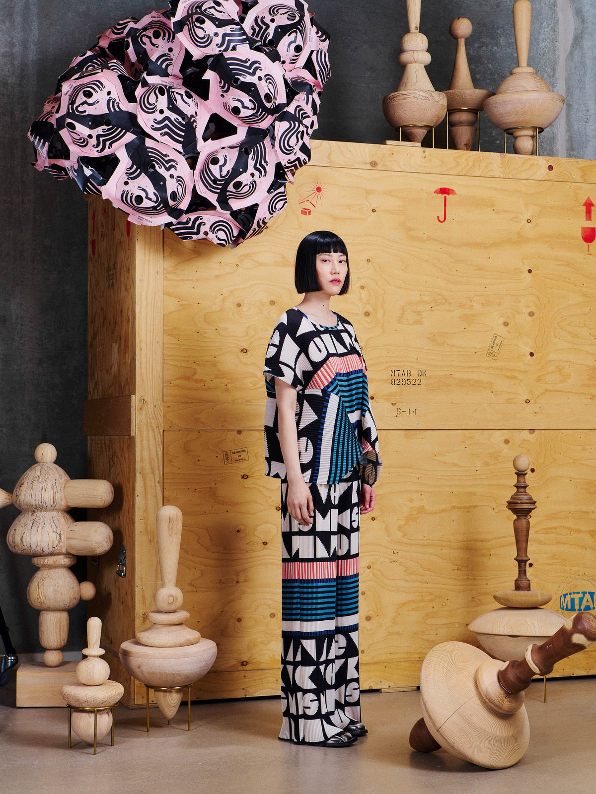 Side view of model wearing Henrik Vibskov Silhouette Plisse Pants in Vibs In Bobs, showing the straight wide-leg shape and graphic pleated fabric.