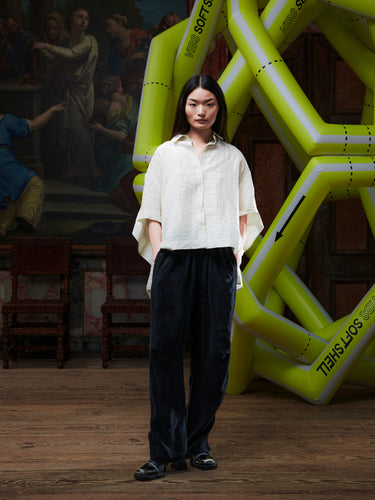 Person wearing a white shirt and black pants standing in front of a large yellow inflatable structure with text.