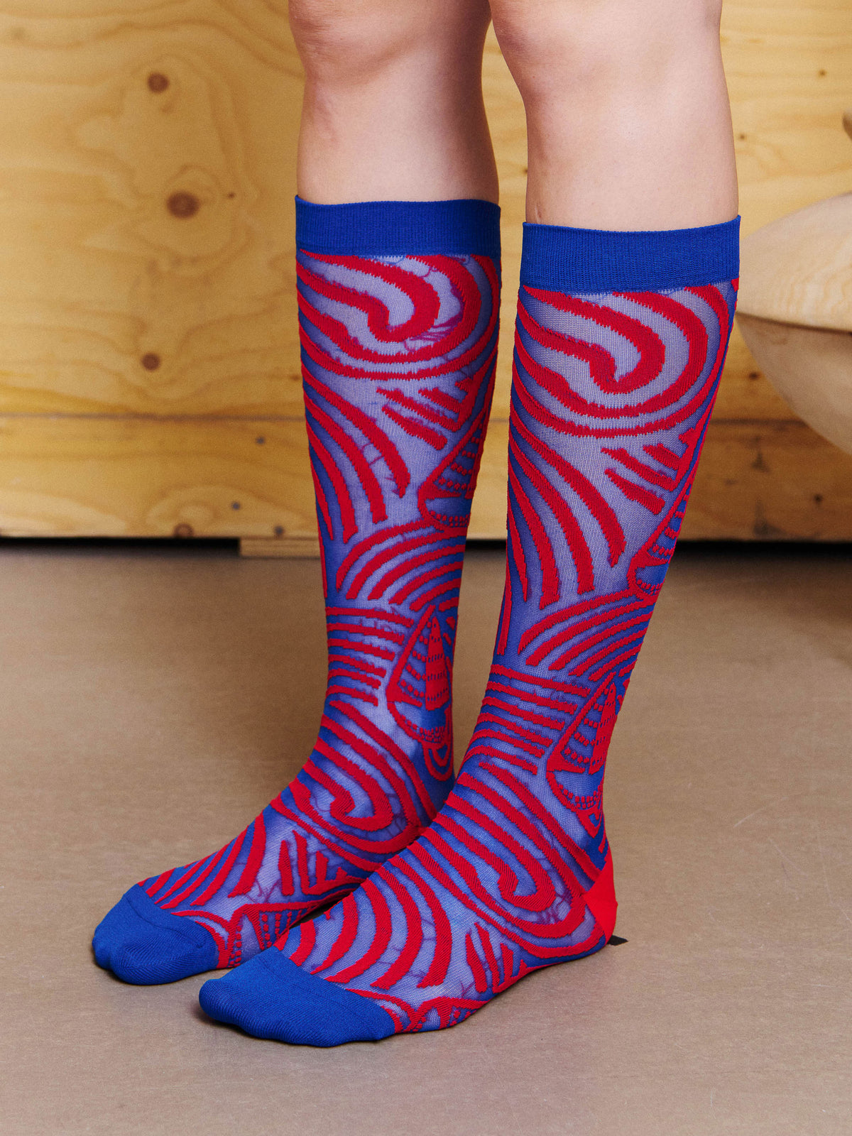 Angled view of model wearing the Henrik Vibskov Stormy Sea Socks in Blue Red Stormy Sea, showing the sailboat motifs, wave pattern and contrast toe.
