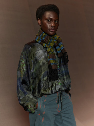 Person wearing a patterned scarf and shirt against a brown background