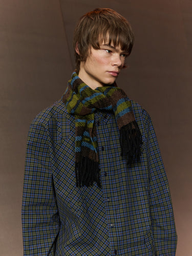Person wearing a plaid shirt and scarf against a brown background