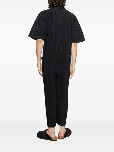 Person wearing a black ribbed jumpsuit on a white background