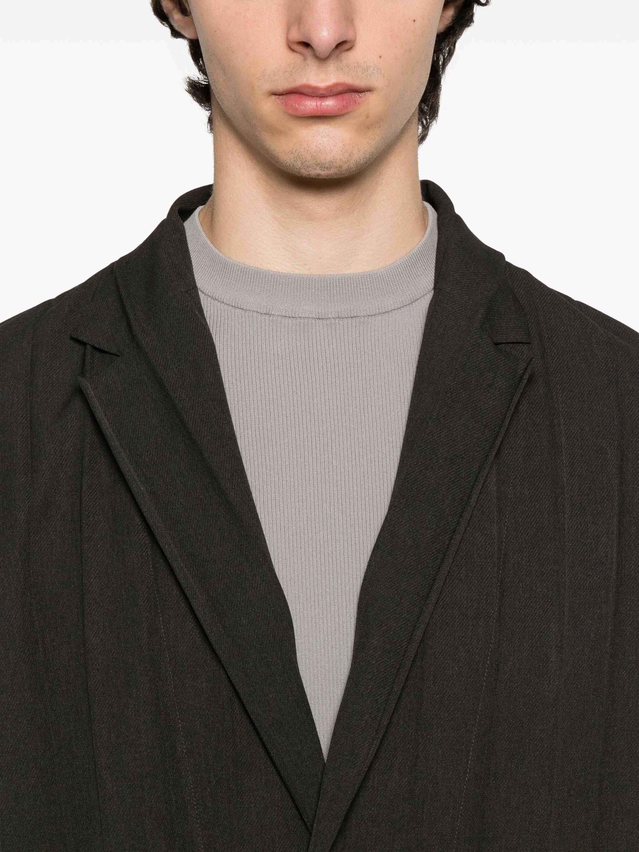 Person wearing a dark brown blazer on a white background
