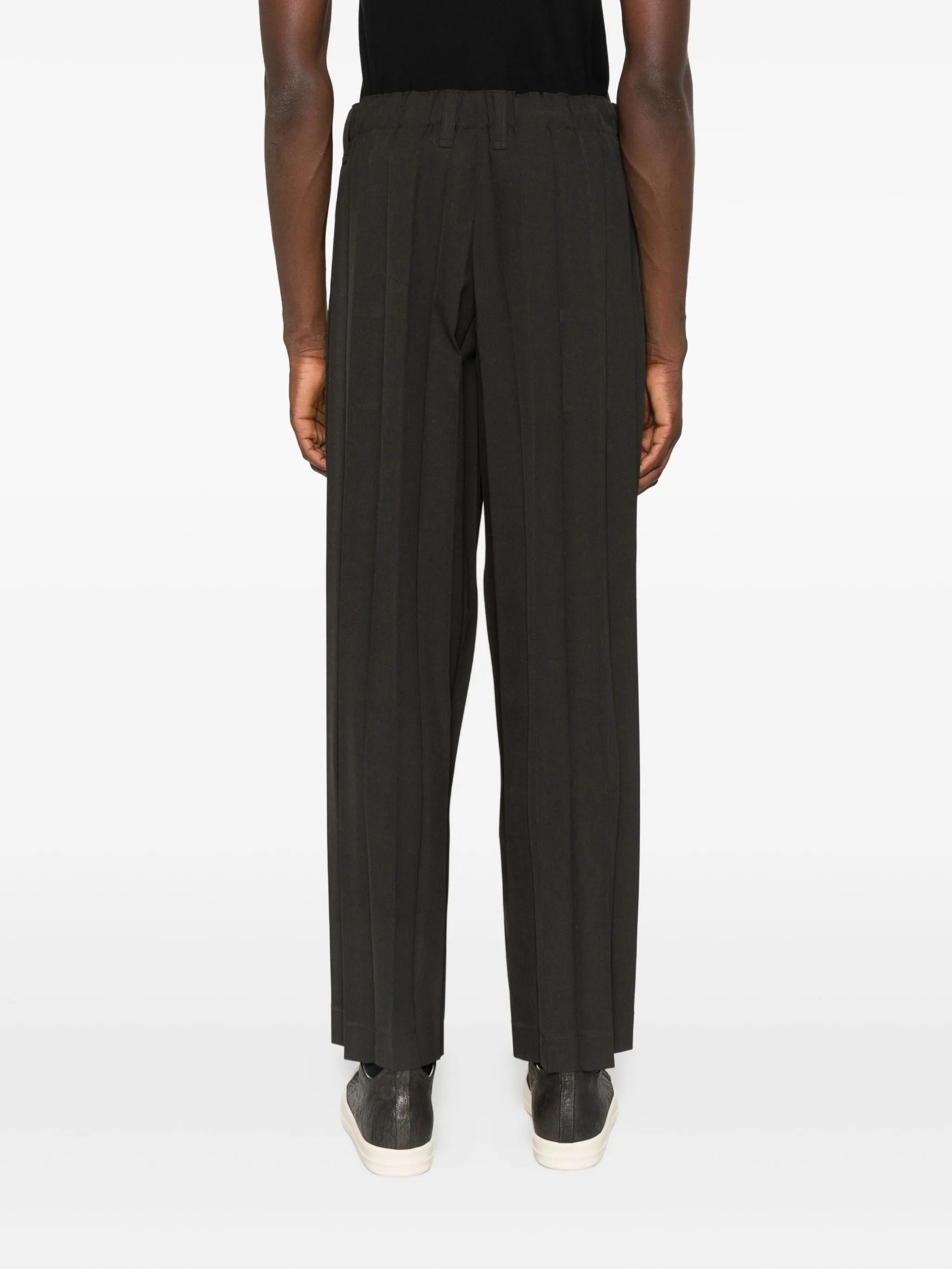 Person wearing dark brown wide-leg pants on a white background
