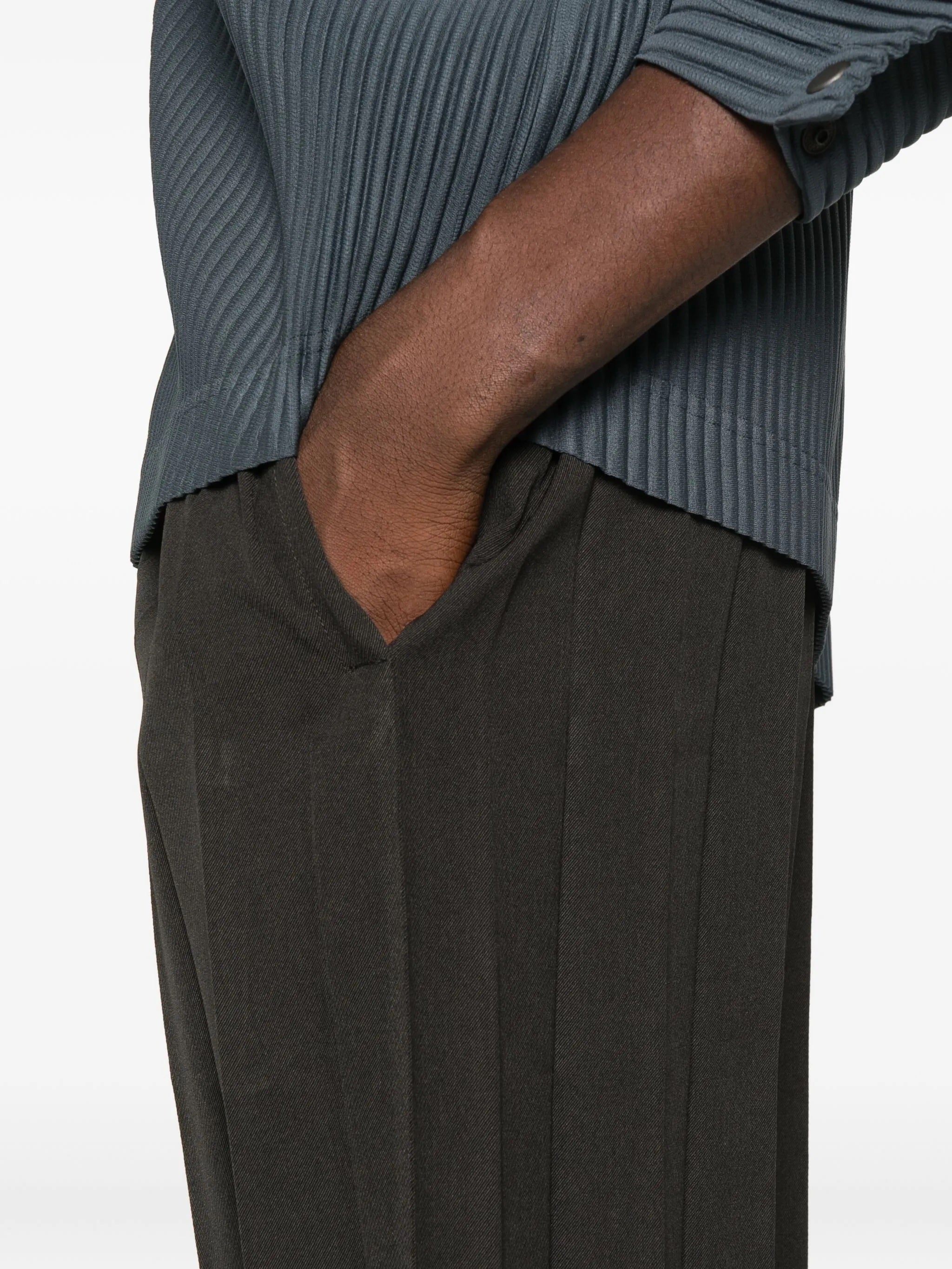 Person wearing a ribbed sweater and pleated pants on a white background